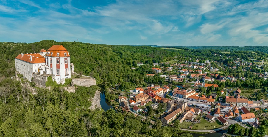 A historic castle on a hill overlooking a town with red-roofed buildings.