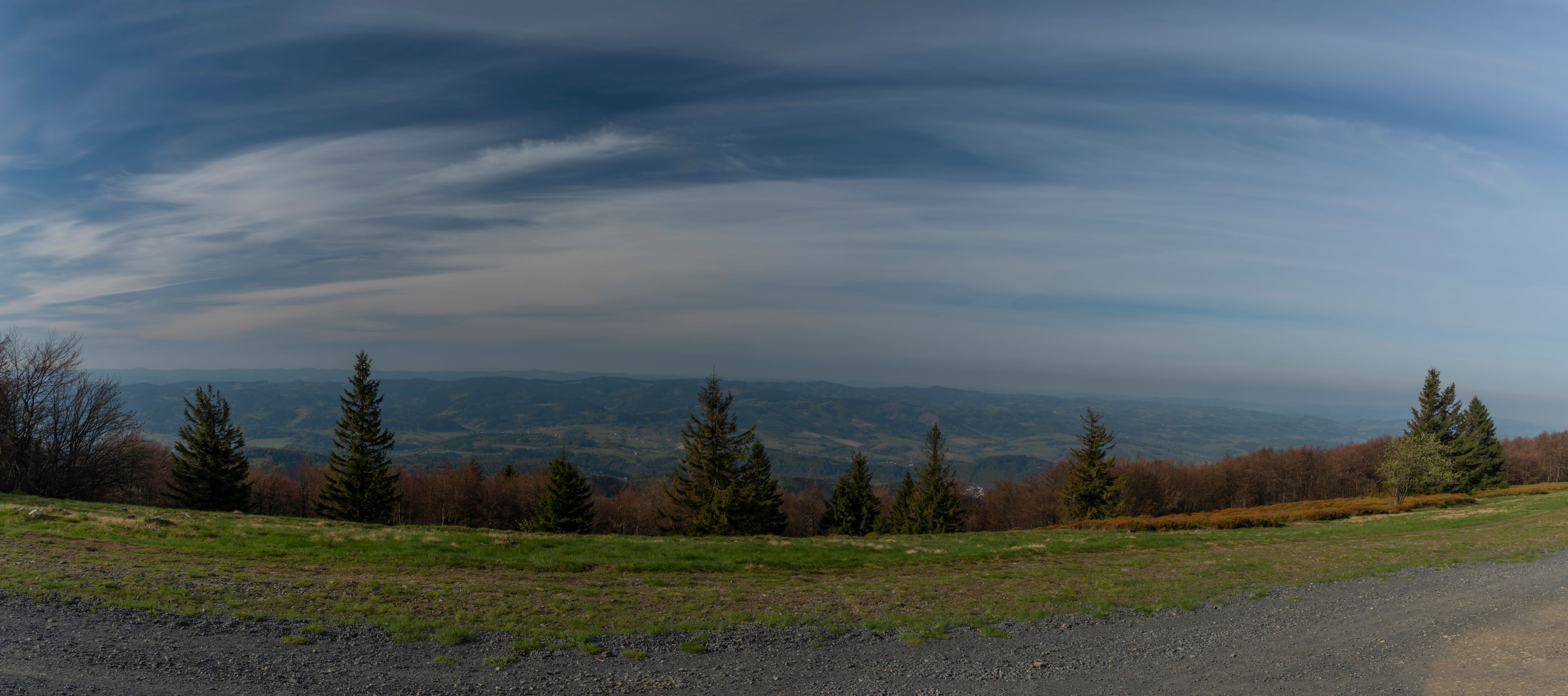 A panoramic view of a mountainous landscape with a clear sky and scattered clouds.