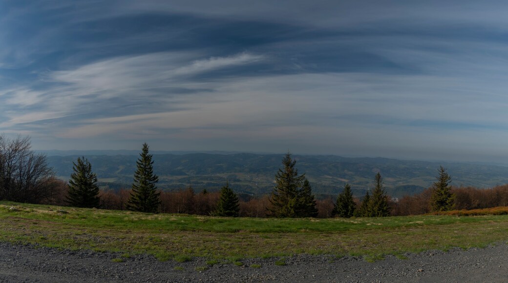 A panoramic view of a mountainous landscape with a clear sky and scattered clouds.