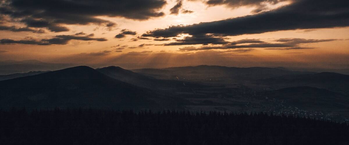 A mountain range with a sunset and clouds.