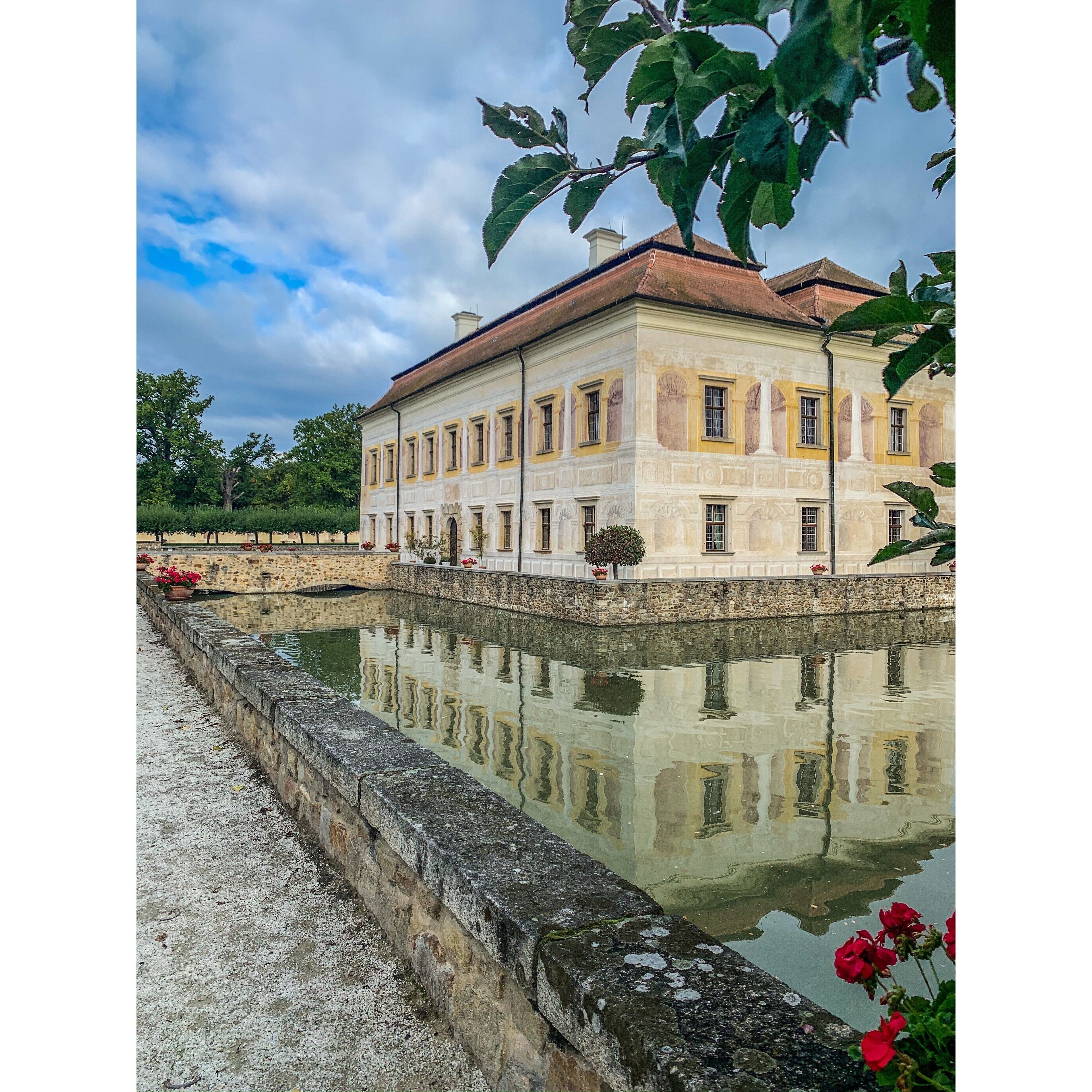 A classical building with a reflective water feature in front.
