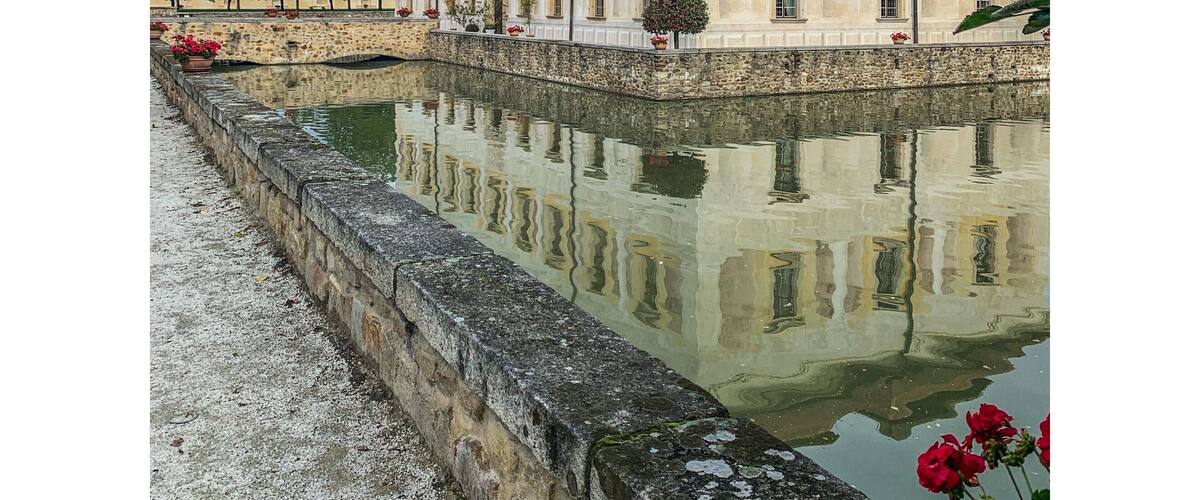 A classical building with a reflective water feature in front.