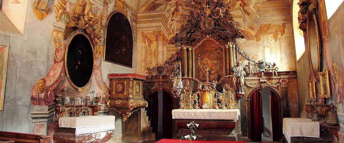 An ornate church interior with a large altar, detailed frescoes, and classical architecture.