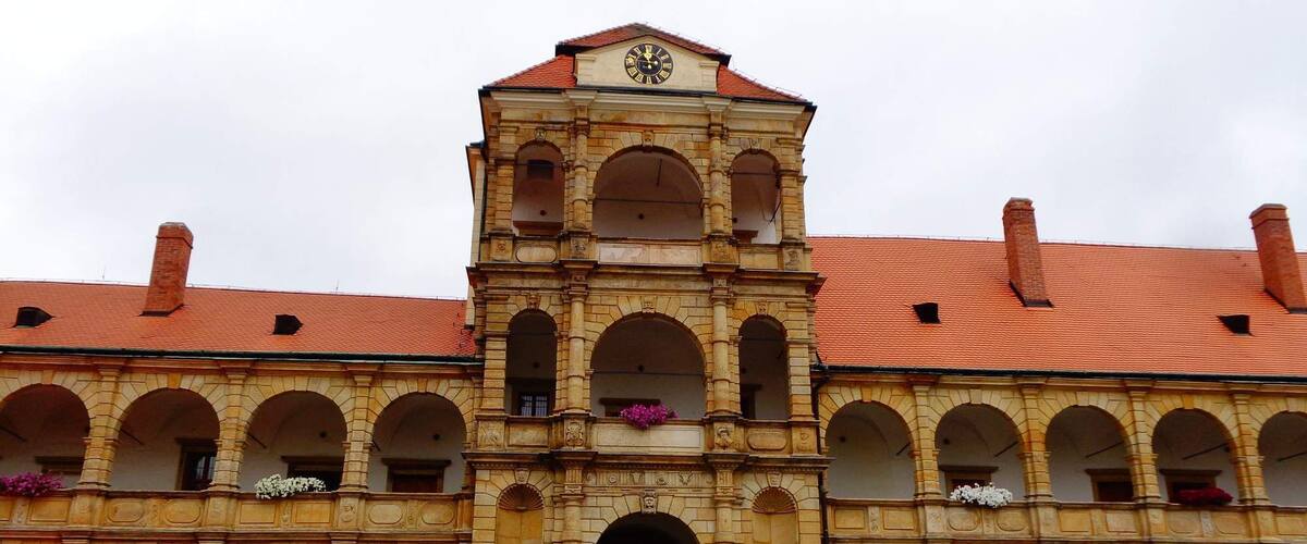A historic building with a central tower, arched windows, and a tiled roof.