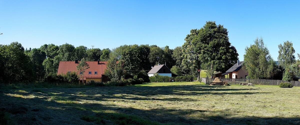 A rural landscape with a red-roofed house, a white house, and a wooden fence.