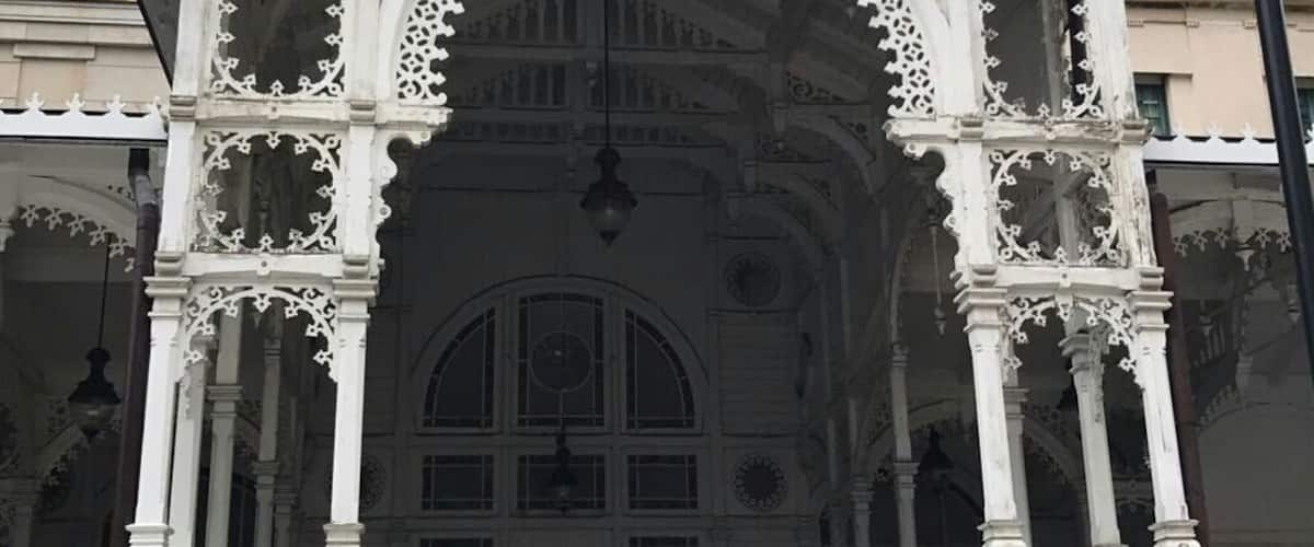An ornate white gazebo with intricate carvings and a person walking in front.