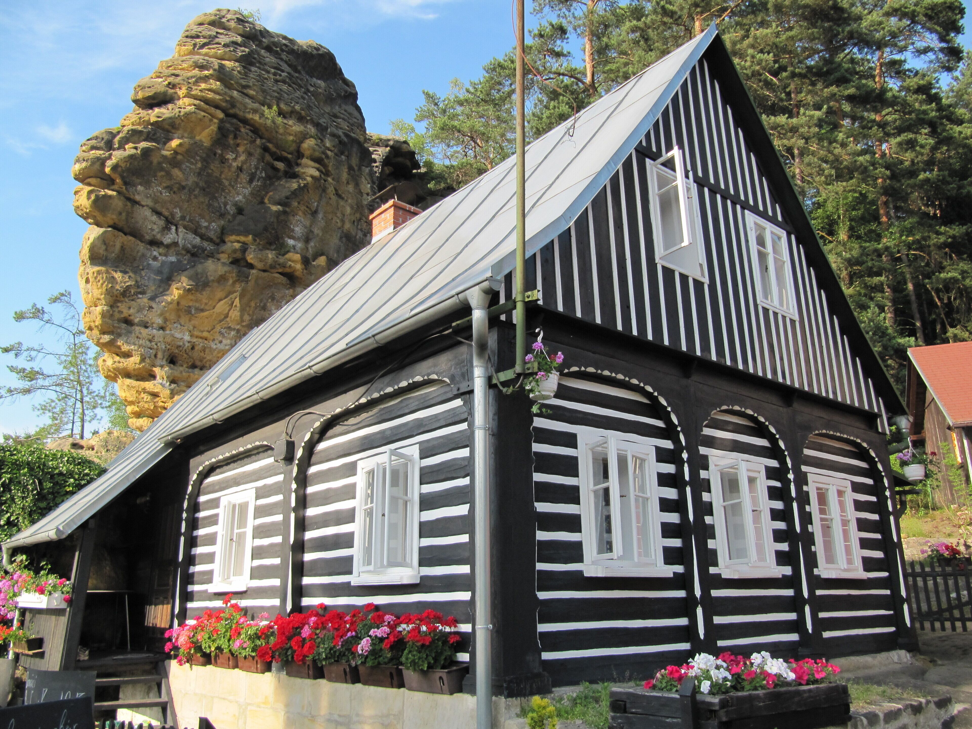 A black and white striped house with a rock formation in the background.