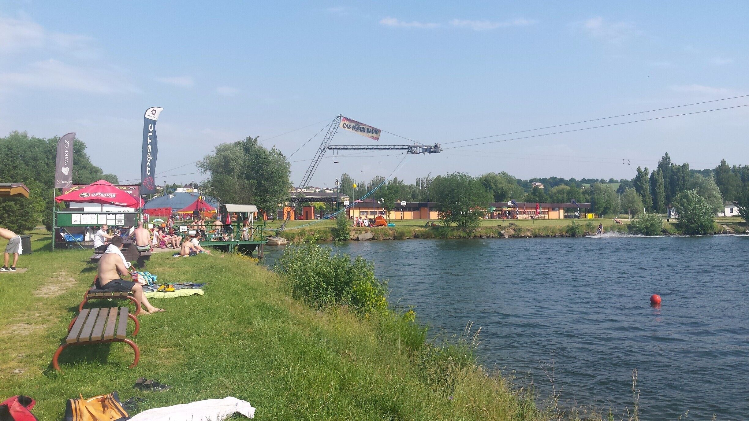 A riverside picnic area with people relaxing and a boat docked on the water.