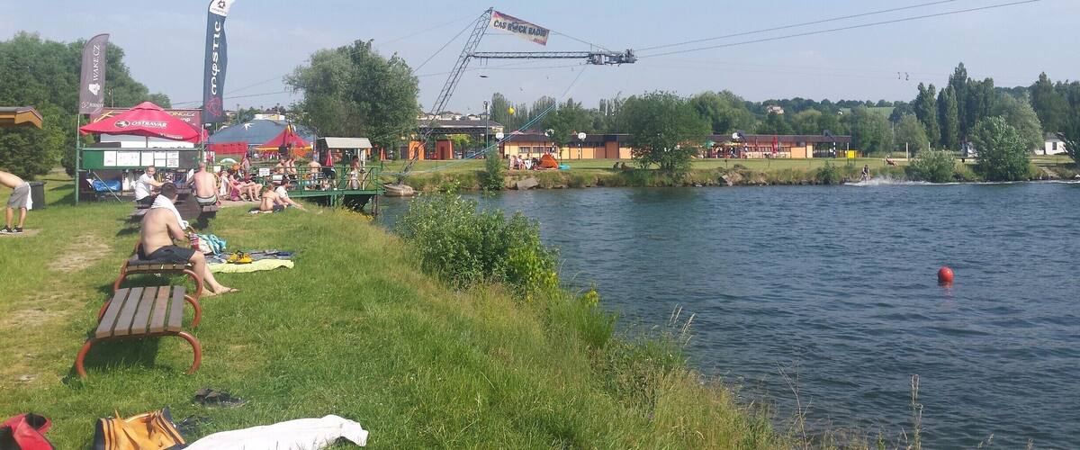 A riverside picnic area with people relaxing and a boat docked on the water.