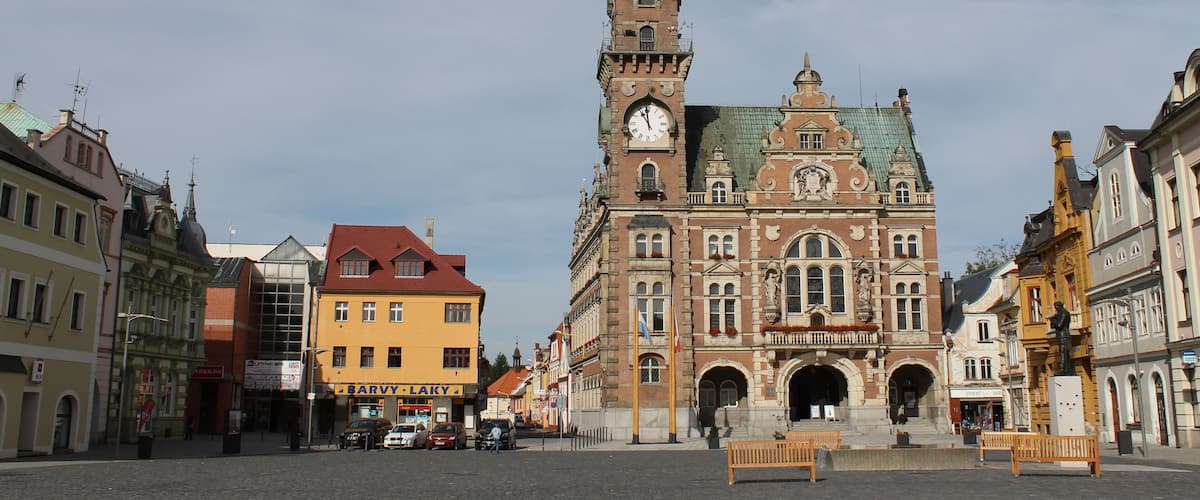 A historic building with a clock tower, a large archway, and a cobblestone square.