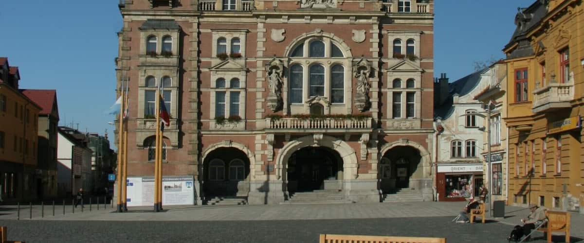 A historic building with a clock tower, arched windows, and a green roof.