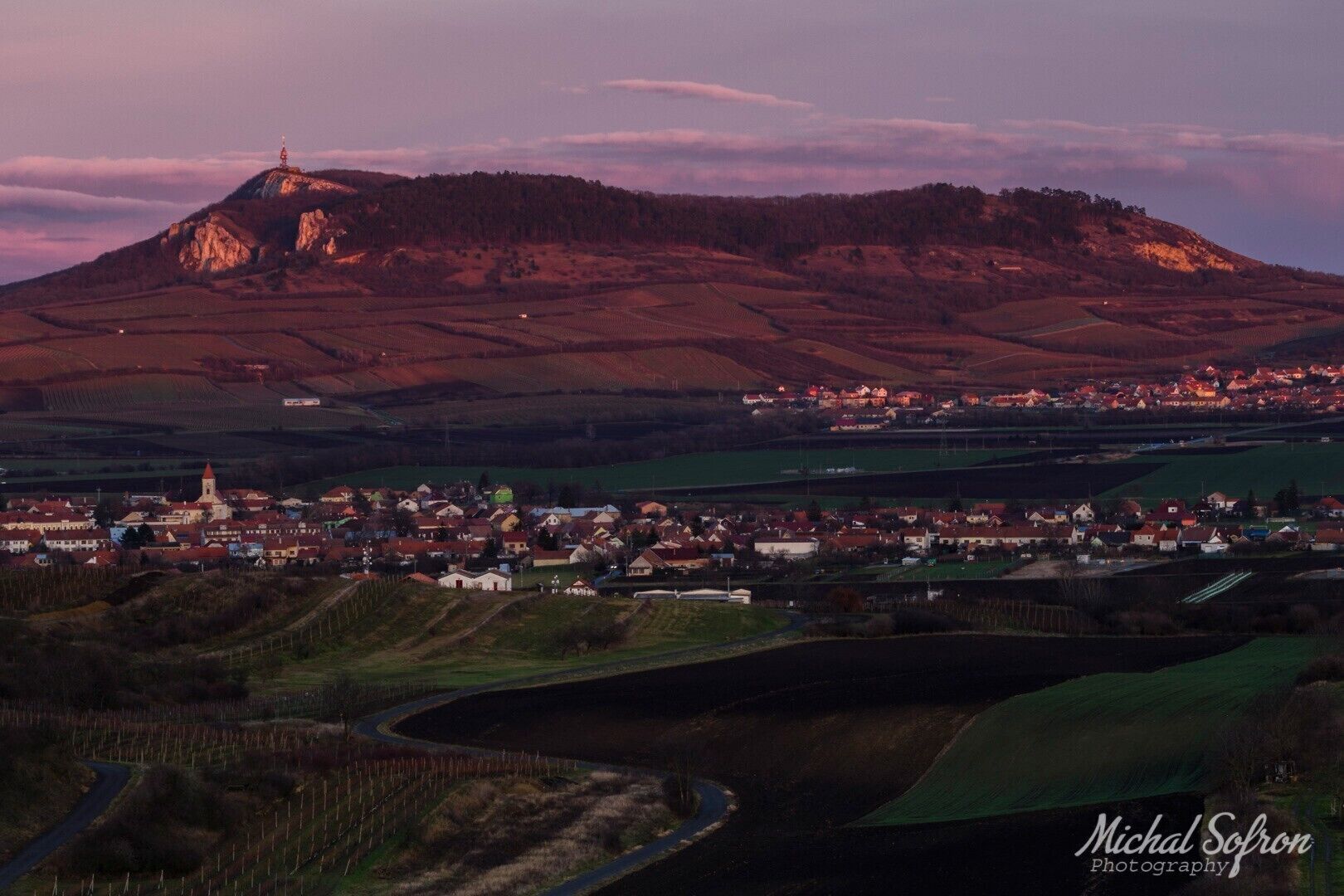 A town nestled in a valley with a prominent hill in the background.