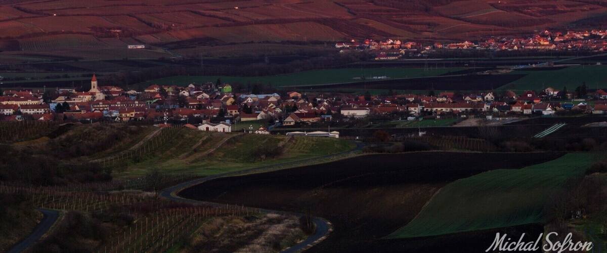A town nestled in a valley with a prominent hill in the background.