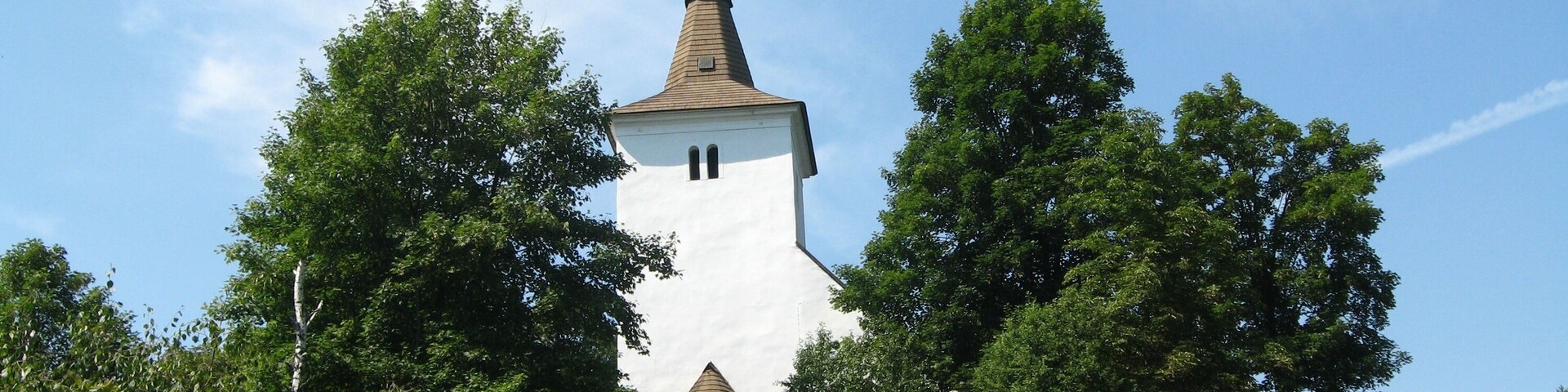 A church with a tall steeple surrounded by trees.