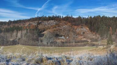 A mountainous landscape with a clear sky, a river, and frost-covered grass.