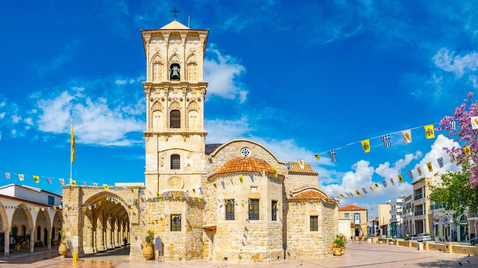 A historic church with a bell tower, arches, and a tiled plaza.
