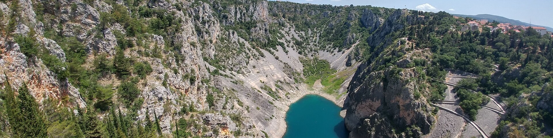 A mountainous landscape with a turquoise lake surrounded by rocky terrain and sparse vegetation.