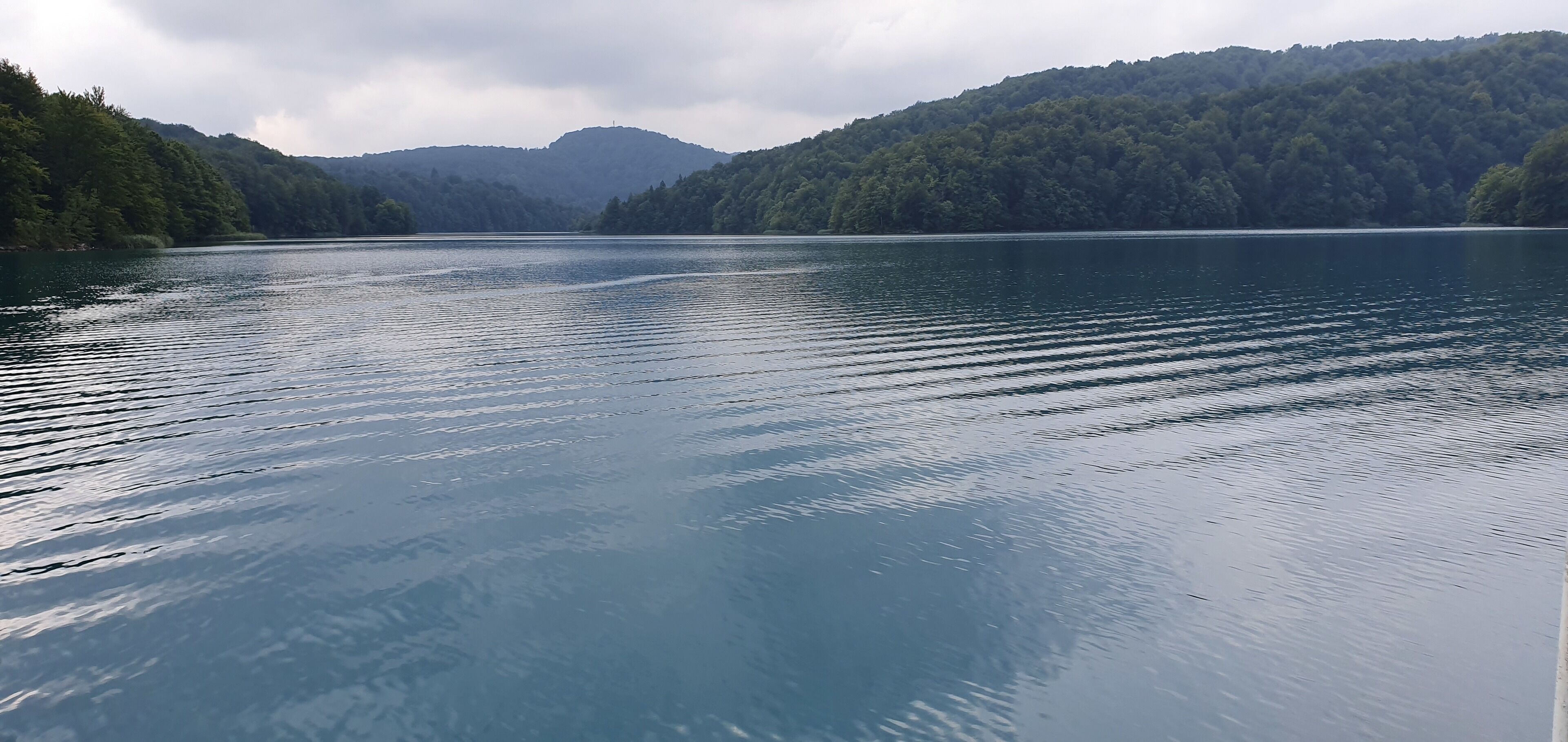 A calm lake surrounded by forested hills.