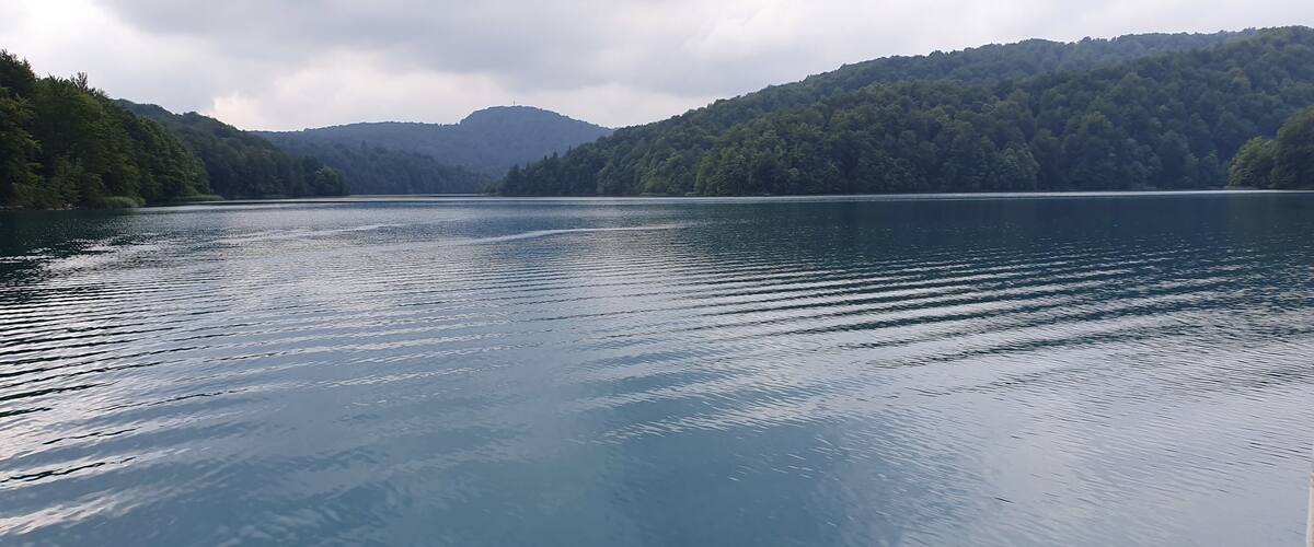 A calm lake surrounded by forested hills.