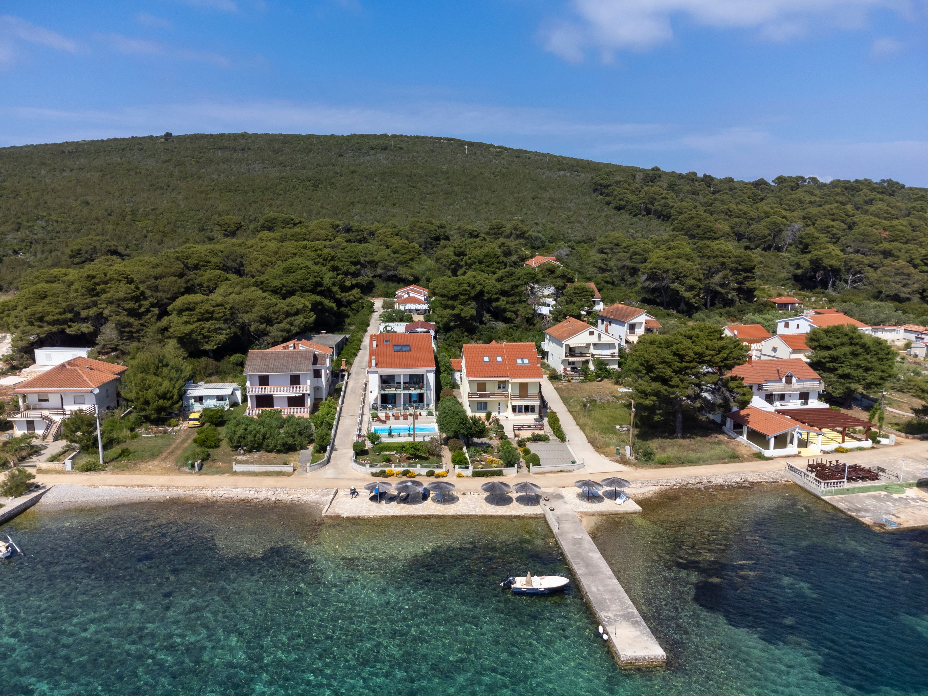 A coastal village with houses, a pier, and clear waters.