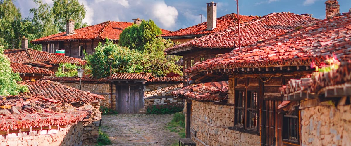A cobblestone street lined with traditional stone houses with red-tiled roofs.