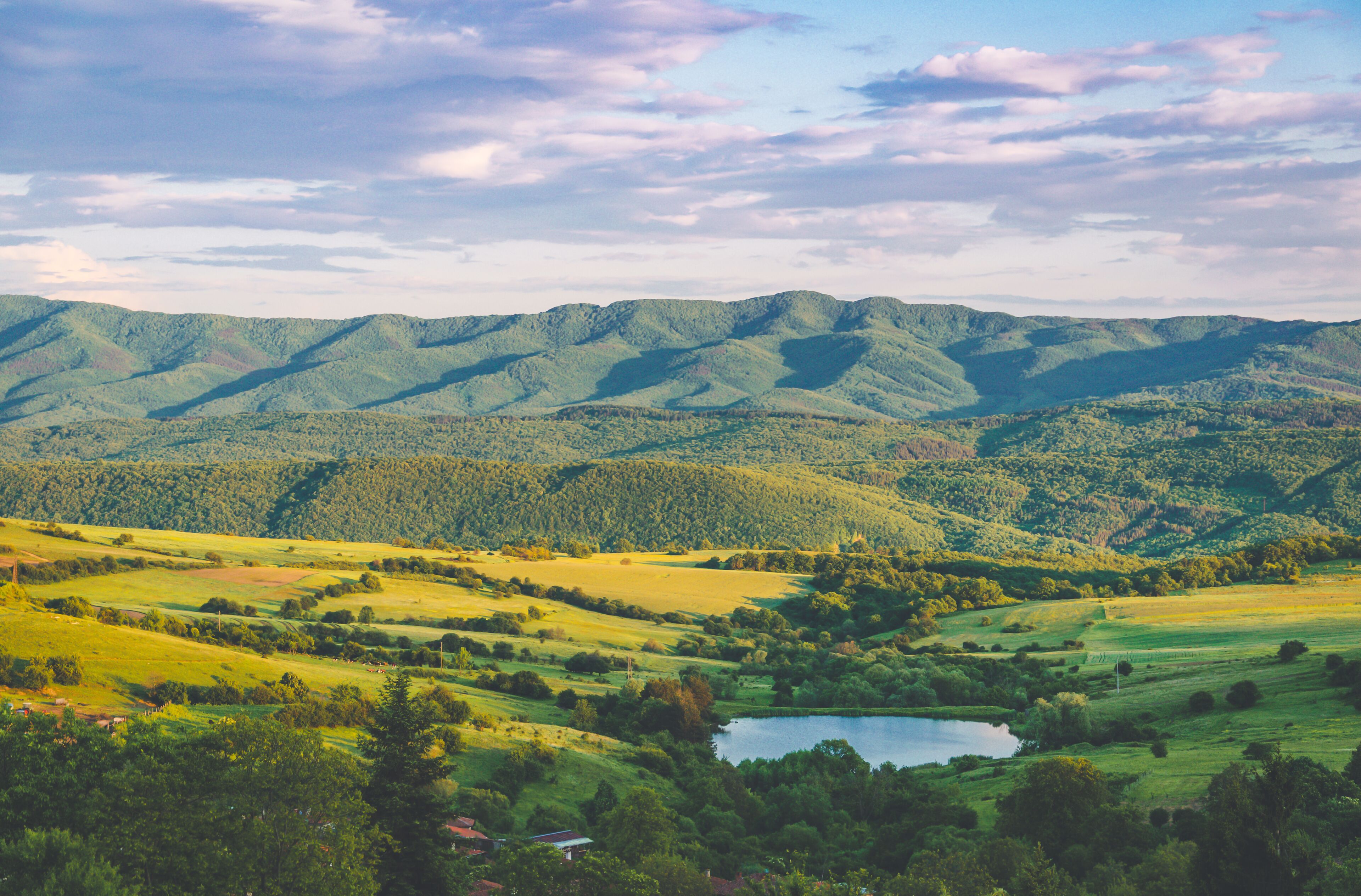 A mountainous landscape with a lake and rolling green fields.