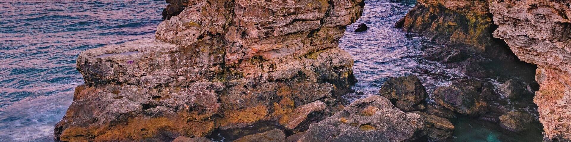 A coastal landscape with a rocky arch formation and the ocean.