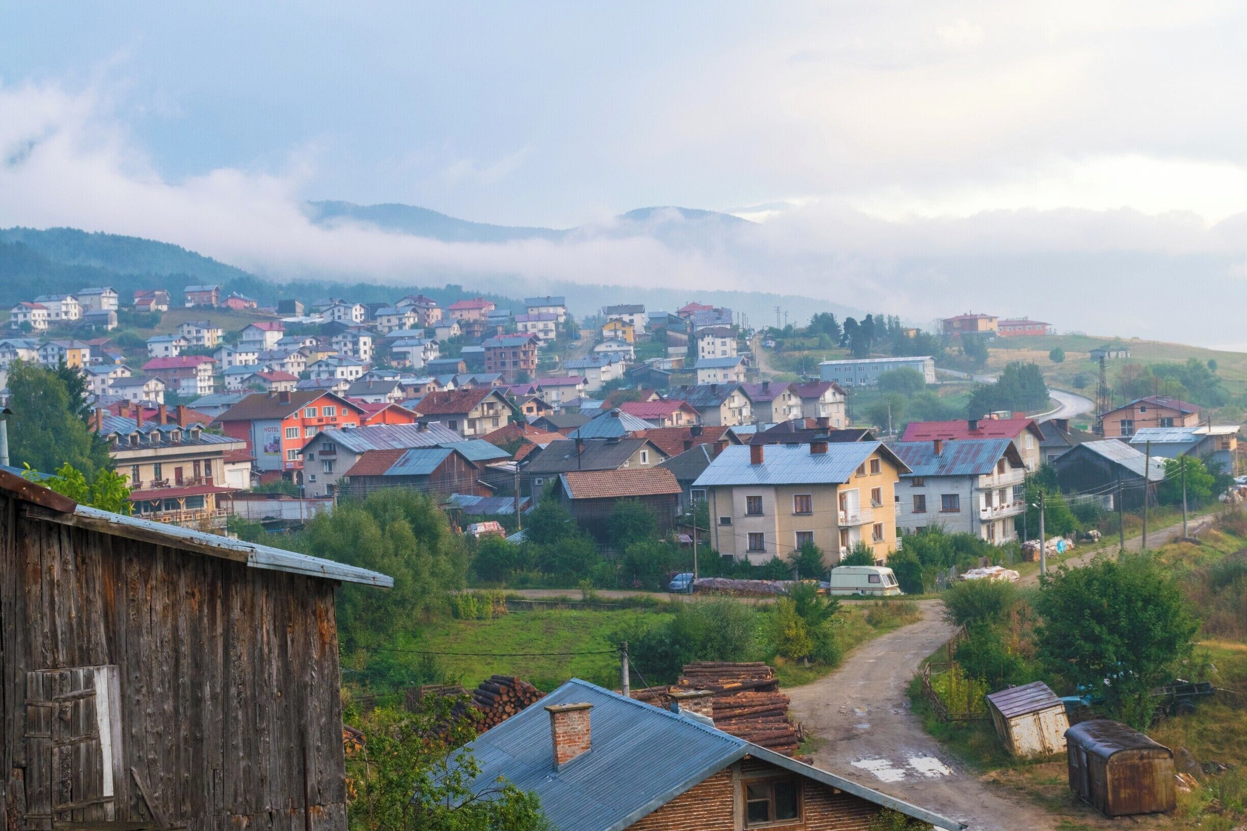 A village with colorful houses, a dirt road, and mountains in the background.