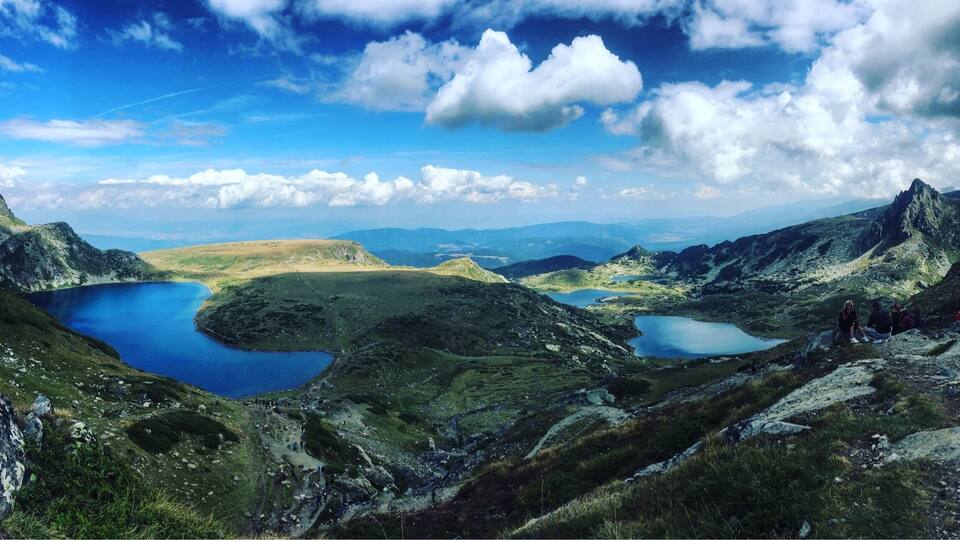 A mountainous landscape with three lakes and a group of hikers.