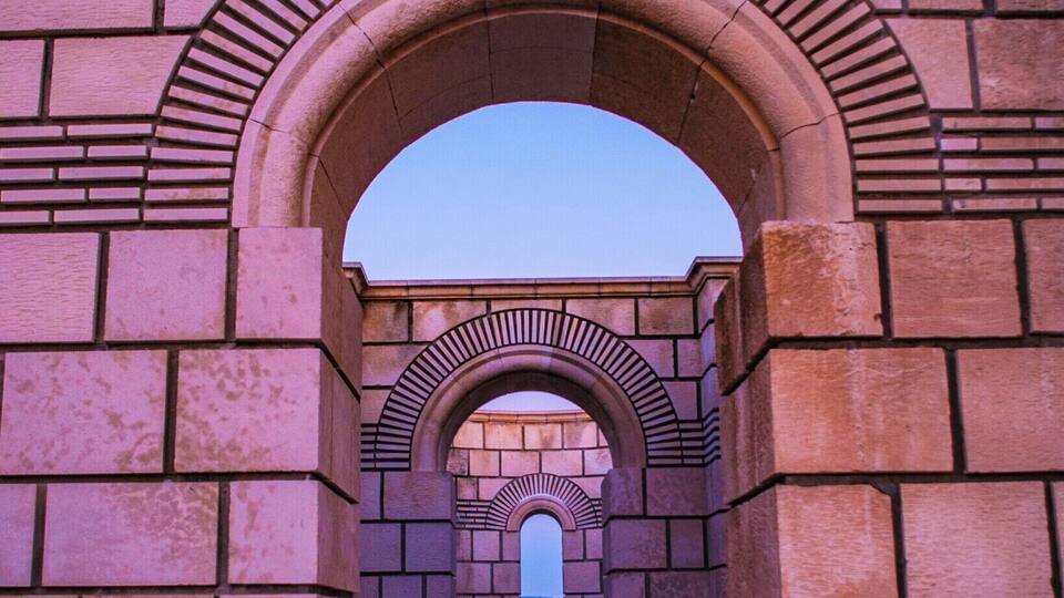 An arched stone gateway with a clear blue sky in the background.