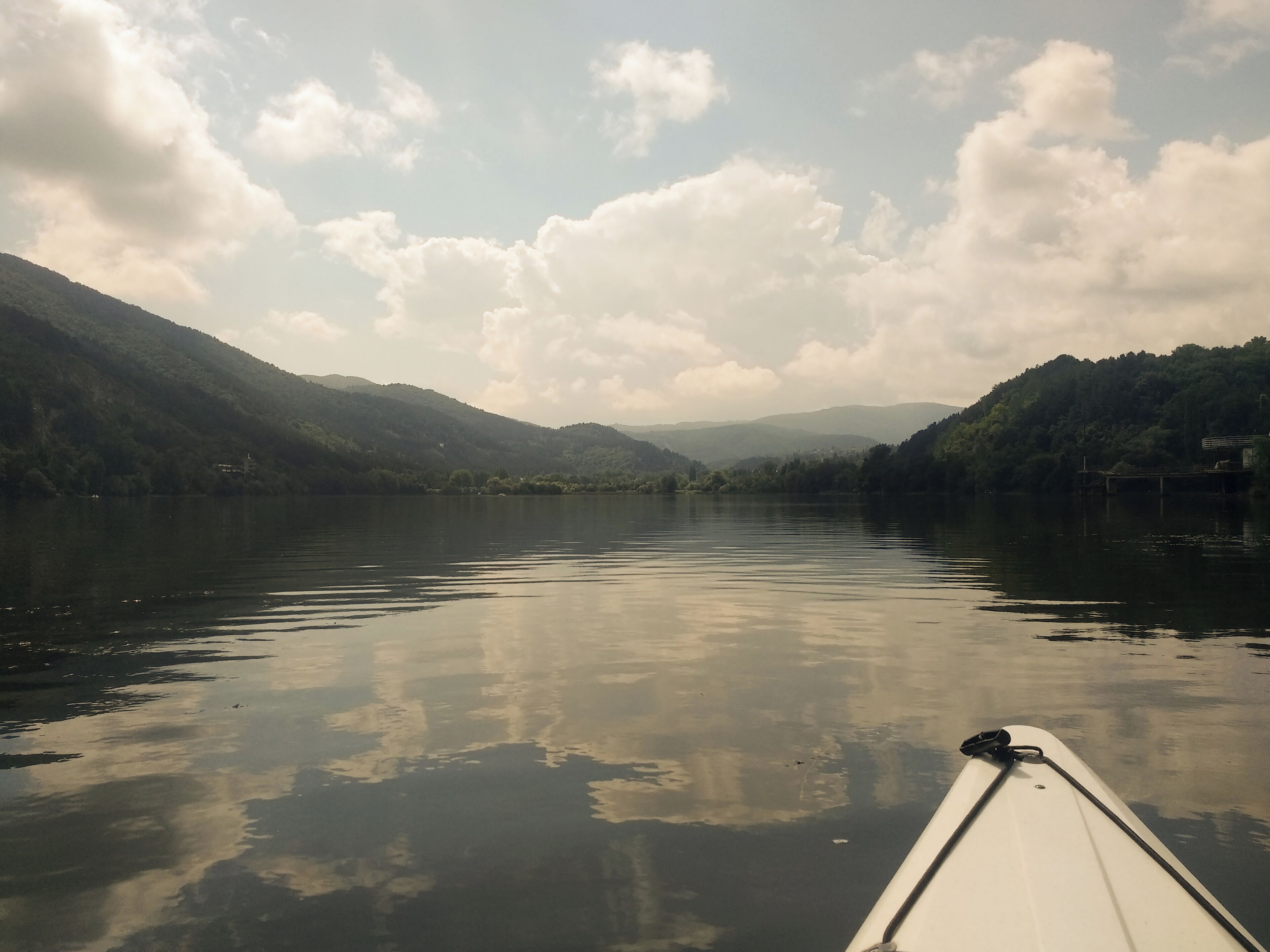 A calm lake with mountains in the background and a boat in the foreground.