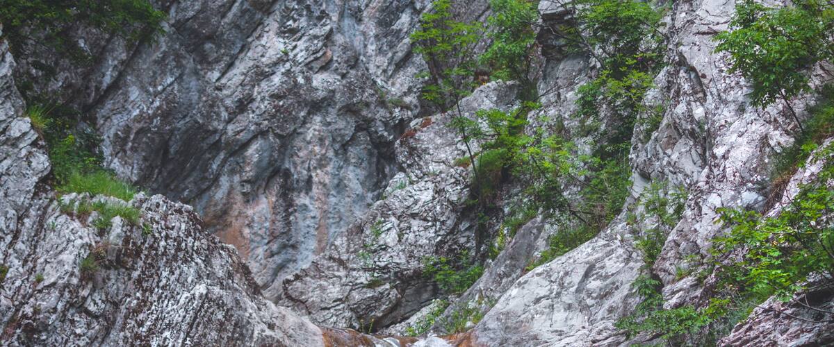 A waterfall cascading down a rocky cliff surrounded by greenery.