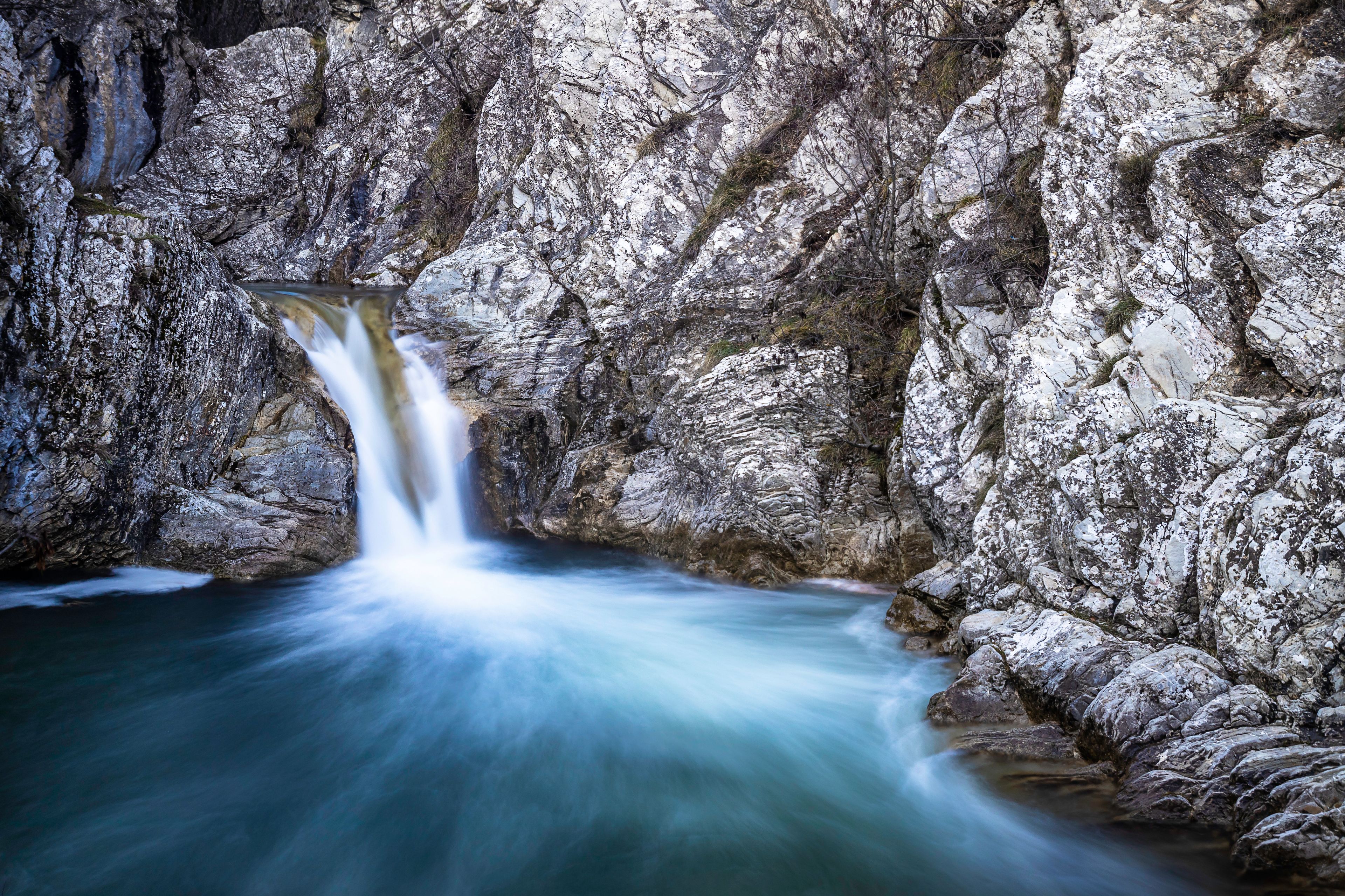 A waterfall cascading down a rocky cliff into a pool below.