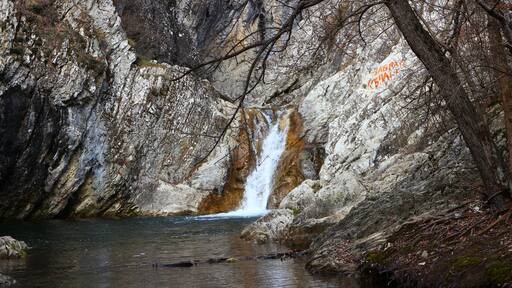 A waterfall cascading down a rocky cliff into a calm pool below.