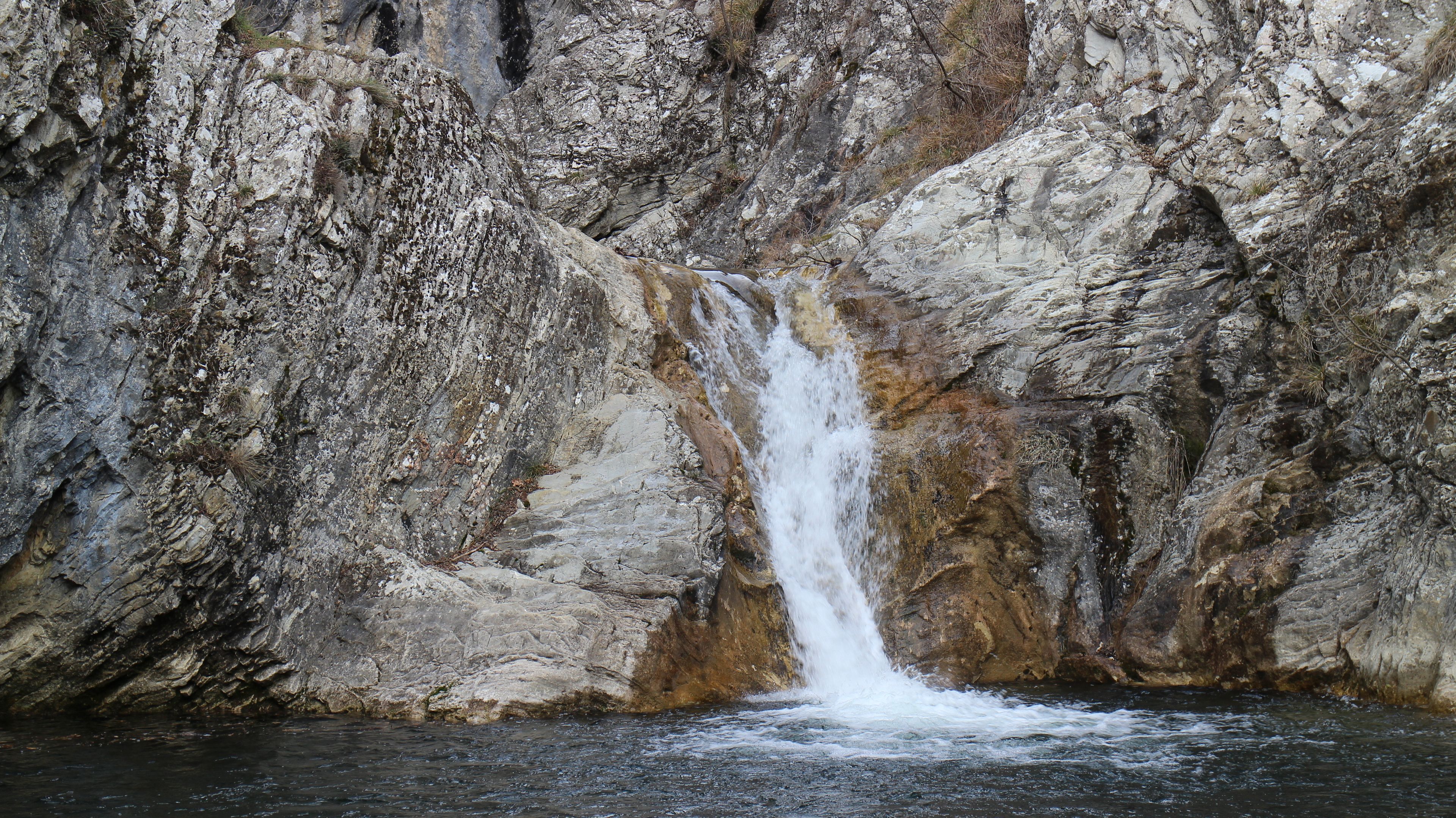 A waterfall cascading down a rocky cliff into a pool of water.