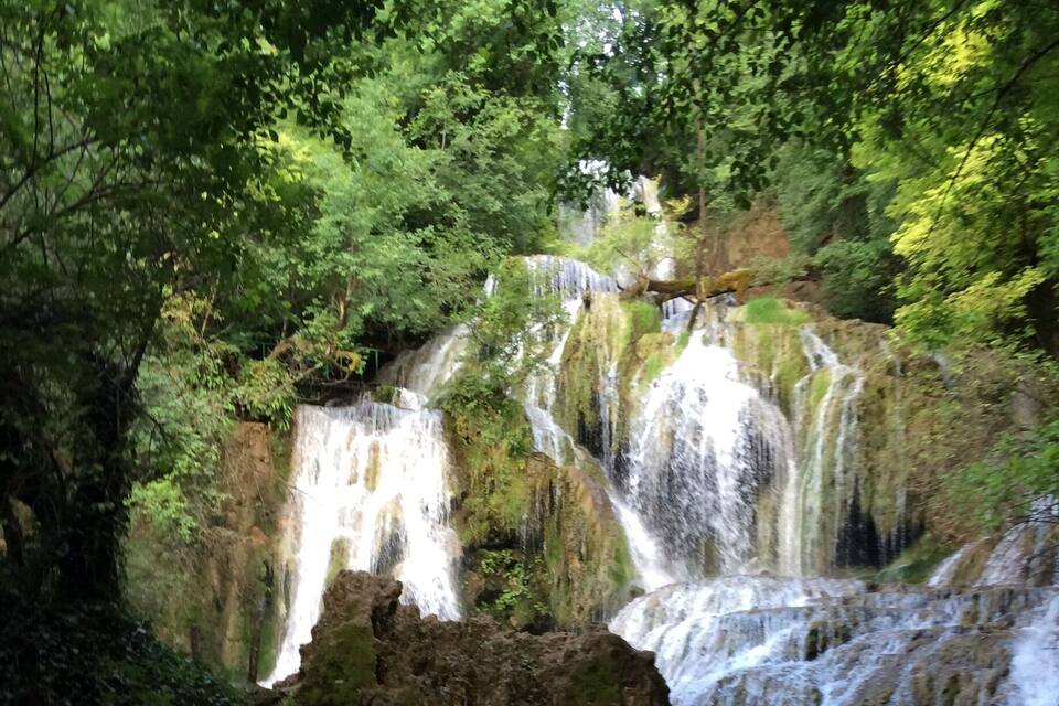 A multi-tiered waterfall surrounded by lush greenery.