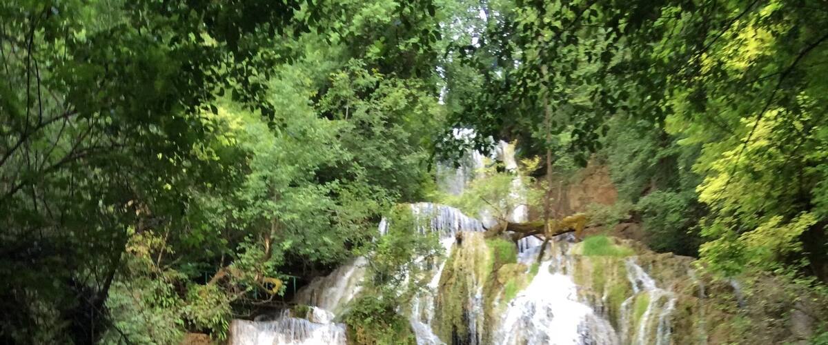 A multi-tiered waterfall surrounded by lush greenery.