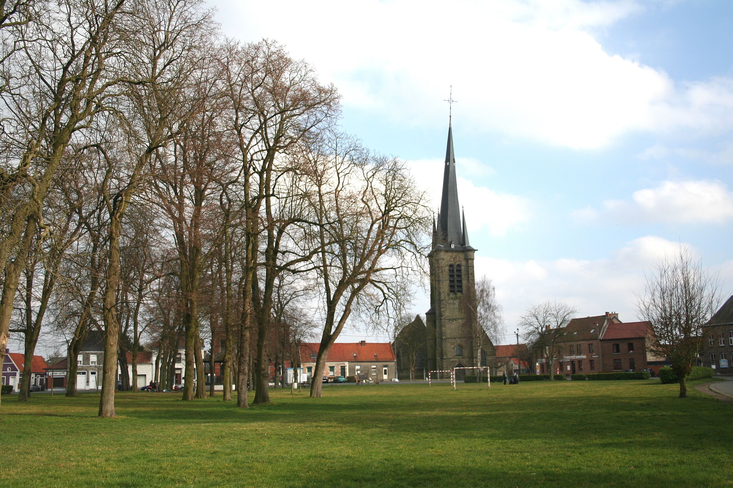 A church with a tall spire, surrounded by trees and buildings.