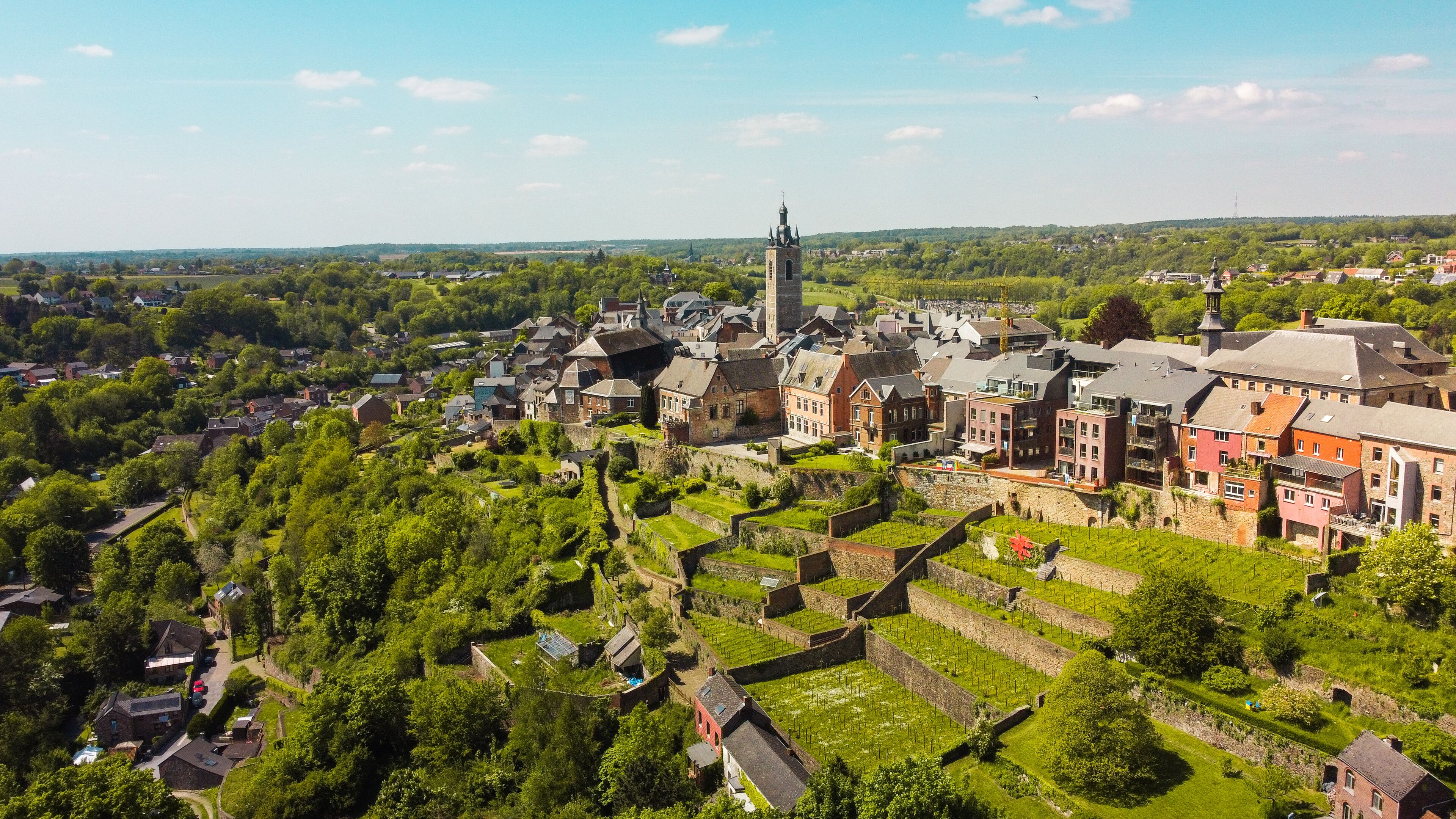 A historic town with a prominent church tower, terraced vineyards, and traditional buildings.