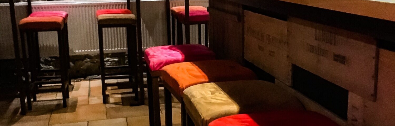 A bar with stools, a stone wall, and a mounted deer head.