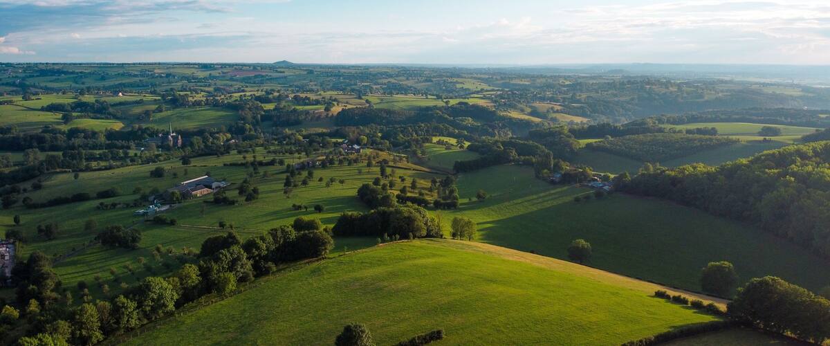Rolling green hills, a church, and a distant mountain range.