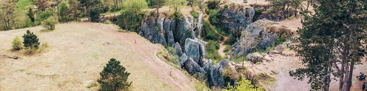 Un paysage montagneux caractérisé par une formation rocheuse imposante, une vallée parsemée d’arbres et un village situé au loin.