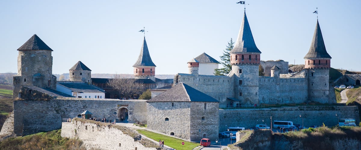A historic castle with multiple towers and a surrounding stone wall.