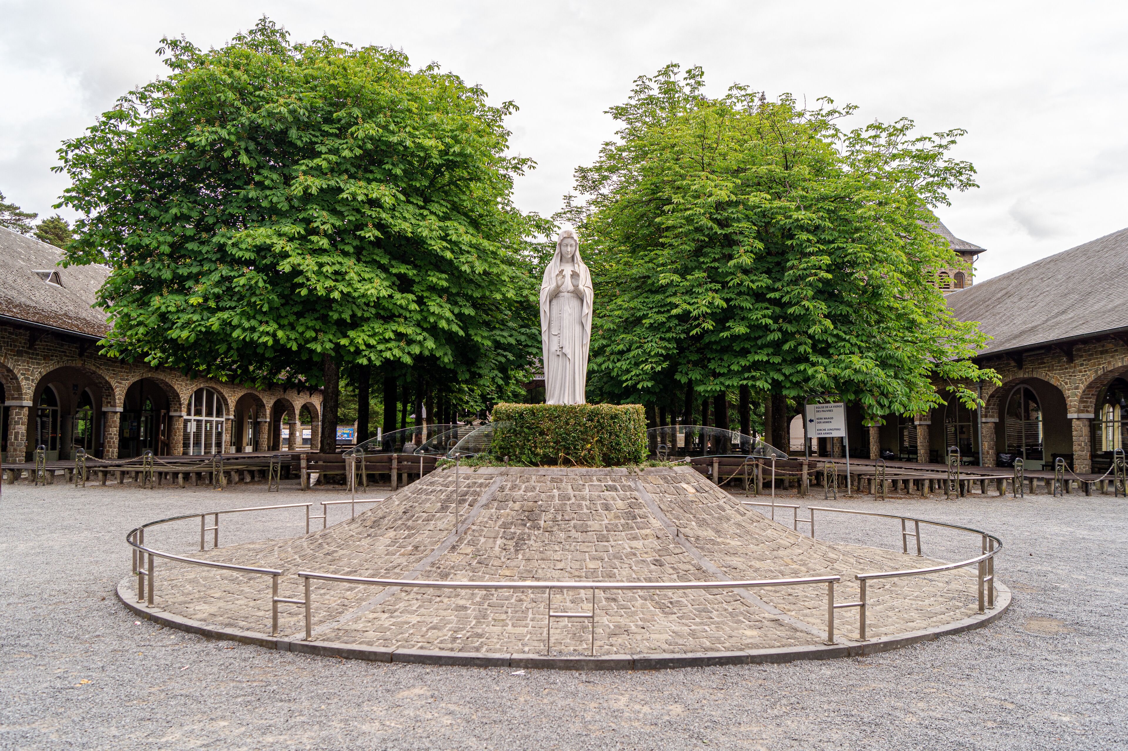 A stone monument in a courtyard surrounded by trees and historic buildings.