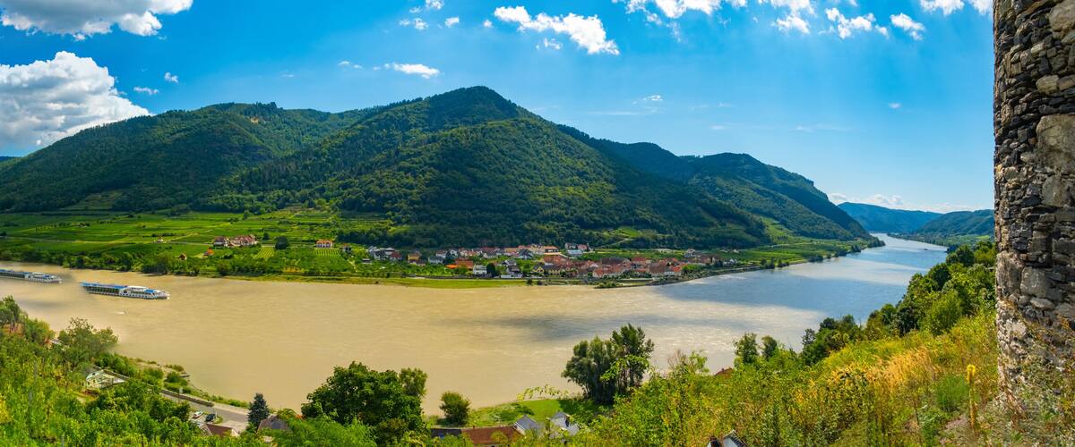 A river winding through a valley with mountains in the background and a stone tower on the right.