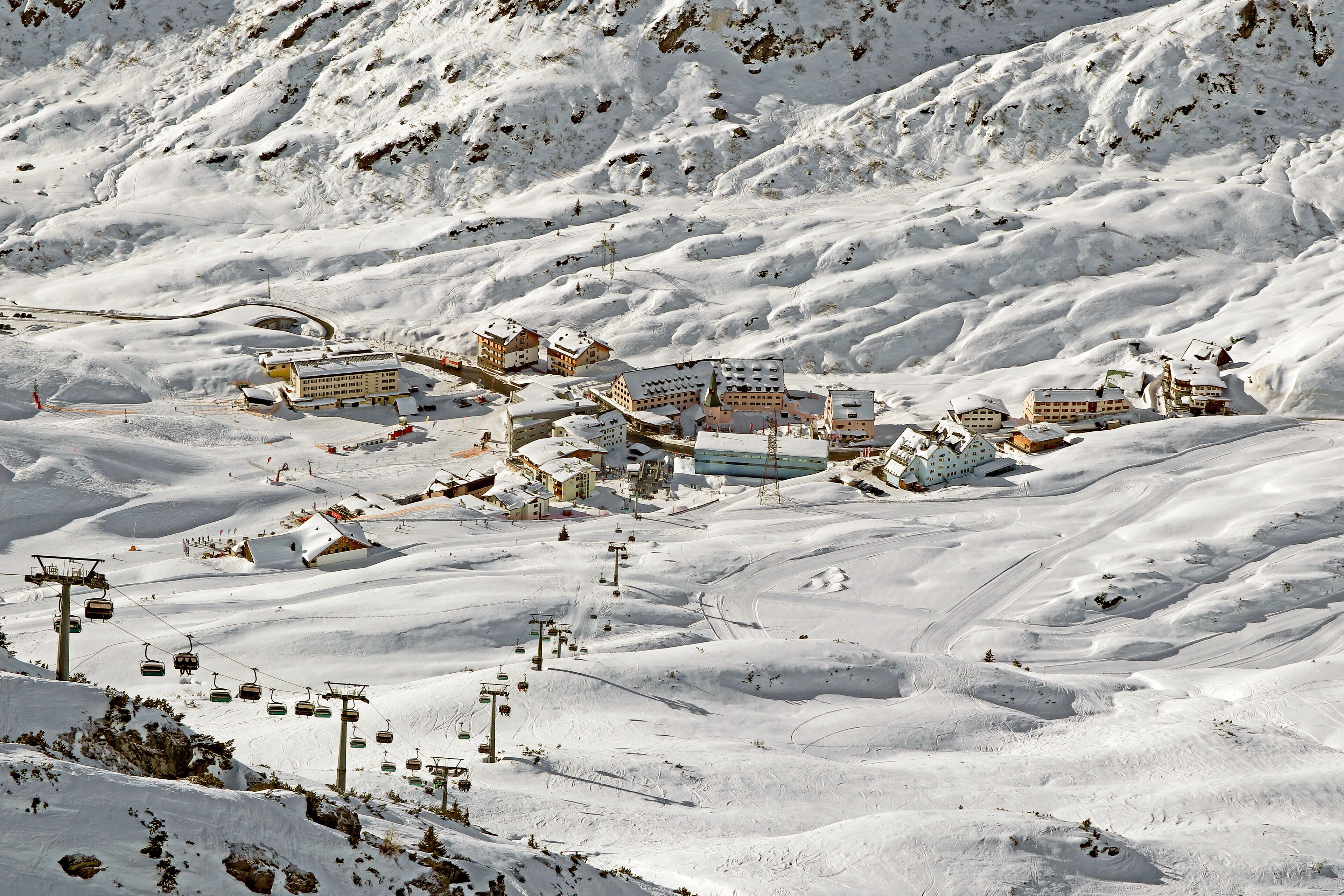 A snow-covered mountain town with ski lifts, buildings, and winding roads.