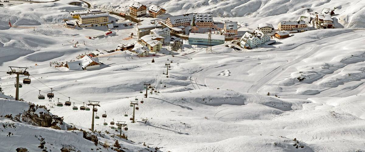 A snow-covered mountain town with ski lifts, buildings, and winding roads.
