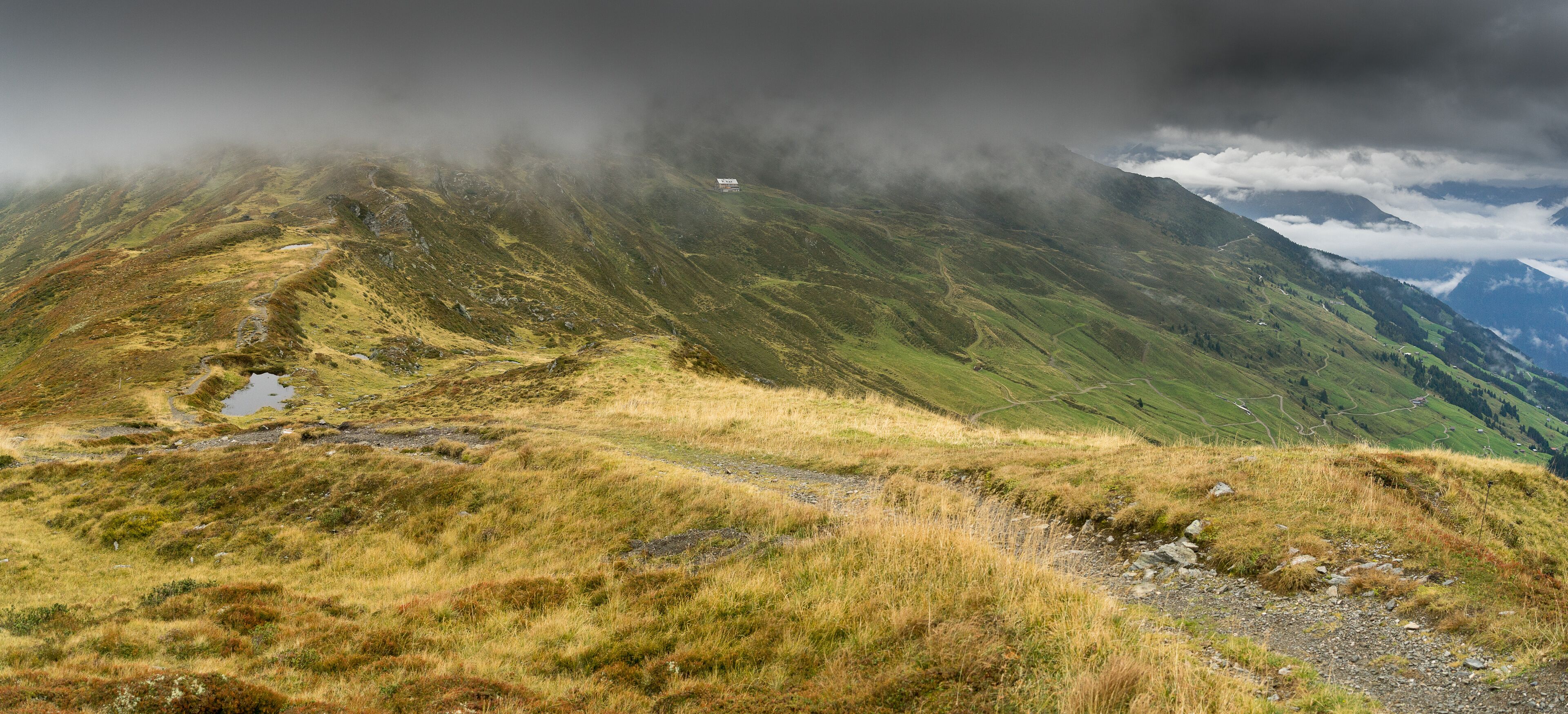 A mountainous landscape with a path leading to a small building.