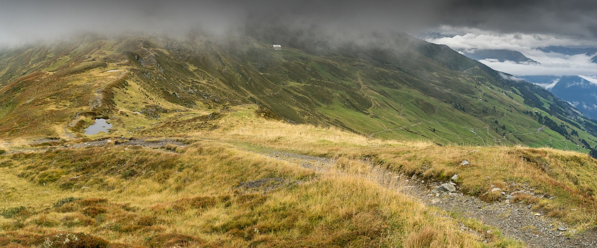 A mountainous landscape with a path leading to a small building.