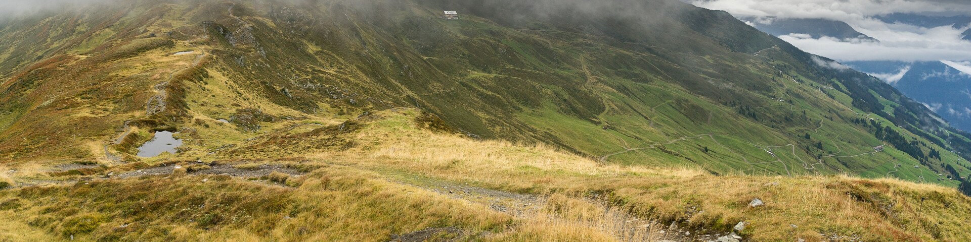 A mountainous landscape with a path leading to a small building.